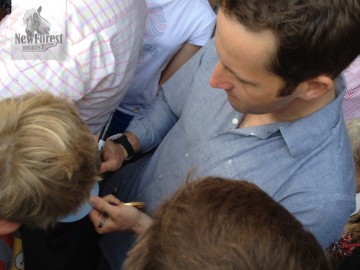 Ben Ainslie signing an autograph, gold medal in hand